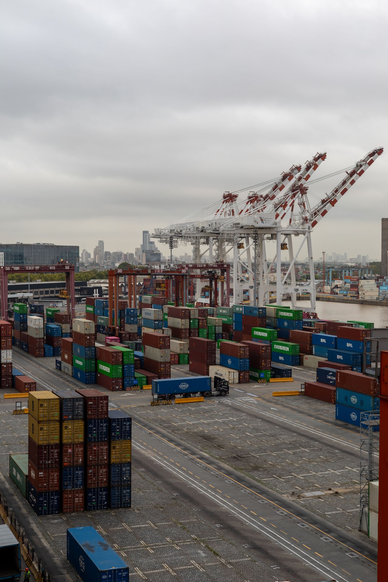 Shipping containers and large gantry cranes at a container port.