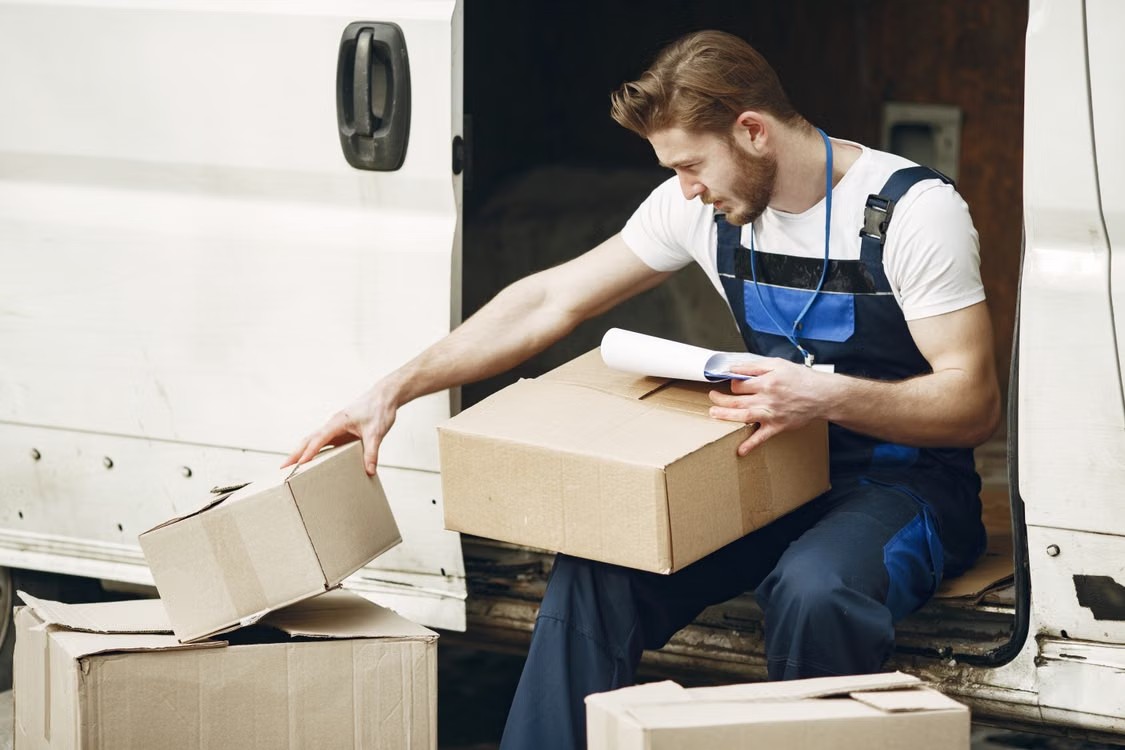 Delivery worker sorting packages beside an open white van